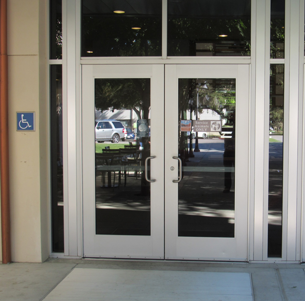 Glass doors with wide aluminum stiles, piano hinges and inset floormat